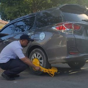Petugas Dishub Makassar menggembok mobil yang terparkir liar di Jalan Pengayoman Makassar, Rabu (15/5/2019).
