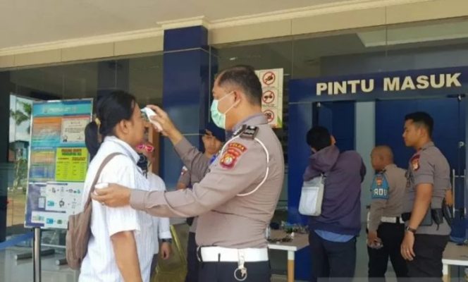 					Petugas memeriksa suhu tubuh pemohon SIM sebagai salah satu protokol pencegahan virus COVID-19 di Satpas SIM Ditlantas Polda Metro Jaya, Daan Mogot, Jakarta Barat, beberapa waktu lalu. (ANTARA/HO/Satpas SIM Ditlantas Polda Metro Jaya)