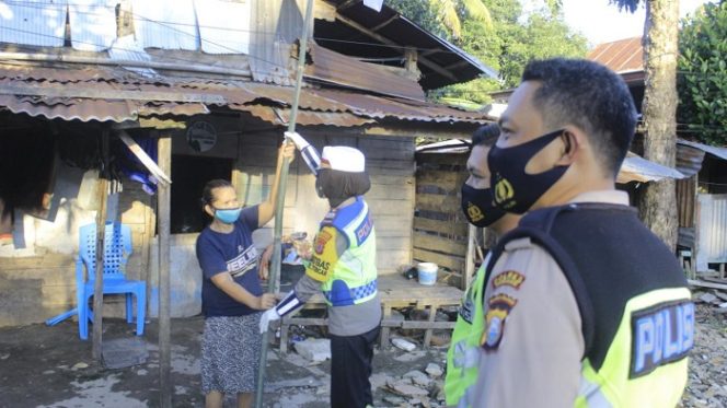 					Kasat Lantas Polres Pinrang AKP Darmawati menyerahkan tiang bendera kepada warga. ()