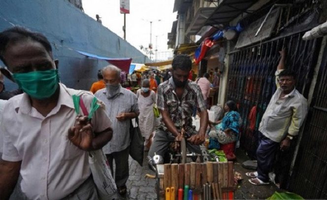 					Seorang penjual keliling mengasah pisau saat duduk di sepedanya dimana warga memakai masker pelindung berjalan melewatinya di sebuah pasar, di tengah penyebaran penyakit virus korona (COVID-19) di Mumbai, India, Kamis (20/8/2020). (REUTERS/Hemanshi Kamani/hp/cfo)
