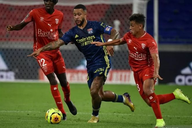 					Aksi pemain Lyon Memphis Depay saat melepaskan diri dari kawalan dua pemain Nimes dalam laga pekan ke-4 Liga Prancis di Stadion Groupama, Jumat (18/9/2020). (ANTARA/AFP/Jean Philippe Ksiazek).