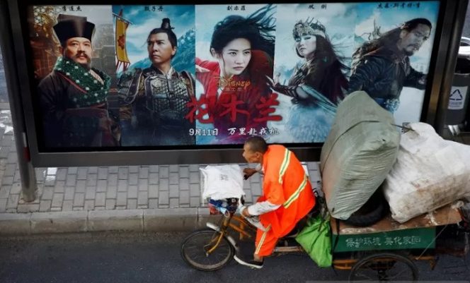 					Seorang pria mengendarai sepeda roda tiga melewati papan reklame mempromosikan film Disney 