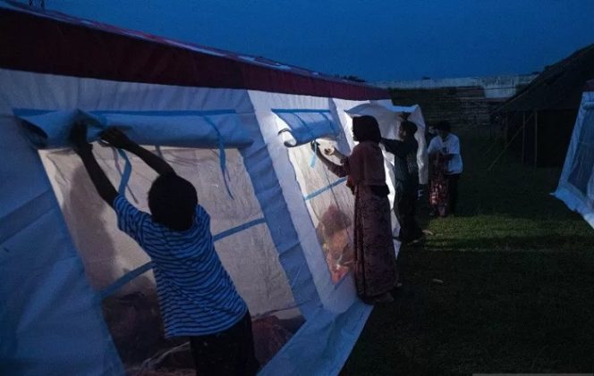 					Sejumlah pengungsi menutup jendela tenda COVID-19 Kementerian Sosial di Stadion Manakarra, Mamuju, Sulawesi Barat, Senin (18/1/2021). ANTARA FOTO/Sigid Kurniawan/foc.