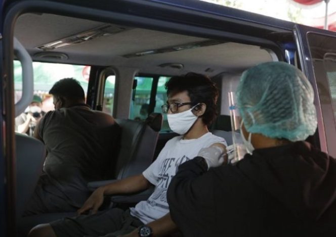 					Petugas saat melakukan vaksinasi terhadap warga dengan sistem drive thru.