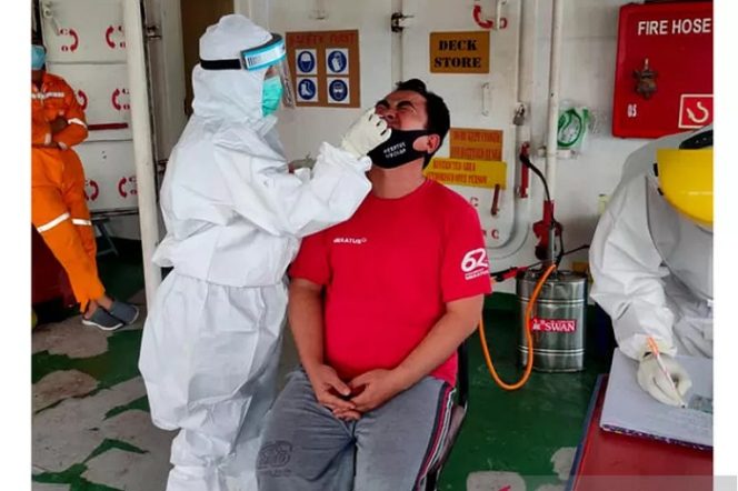 					Petugas Kantor Karantina Pelabuhan (KKP) Kupang, Provinsi Nusa Tenggara Timur sedang mengambil sampel seorang kru kapal kargo yang baru tiba di Kupang. (FOTO ANTARA/HK-KKP Kupang/2021).