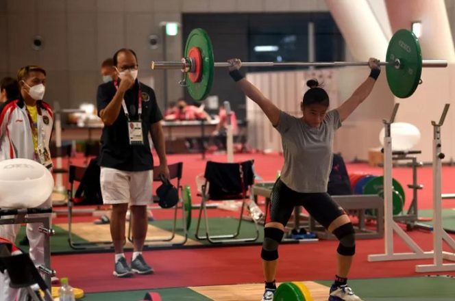 					Lifter putri Indonesia Windy Cantika Aisah (kanan) melakukan angkatan saat sesi latihan disaksikan CdM Kontingen Indonesia Rosan Roeslani (tengah) dan Kepala Pelatih Angkat Besi Dirja Wihardja (kiri) di Arena Angkat Besi Olimpiade Tokyo 2020, Tokyo International Forum, Tokyo, Jepang, Kamis (22/7/2021). ANTARA FOTO/Sigid Kurniawan/rwa. (ANTARA FOTO/SIGID KURNIAWAN)