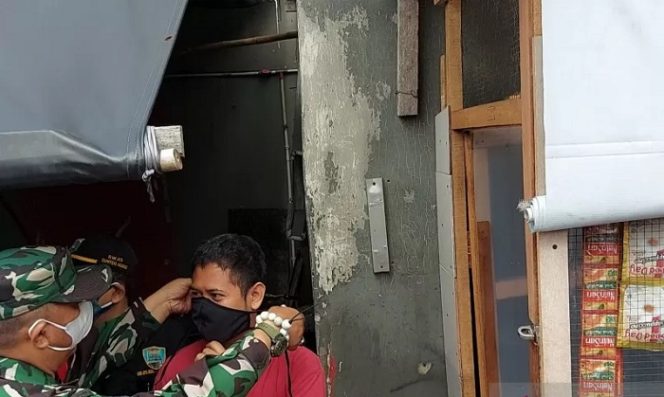 					Bintara Pembina Desa (Babinsa) Kelurahan Sunter Agung Serma Laode Arifudin memasangkan masker kepada pedagang yang kedapatan belum vaksinasi COVID-19 dan tidak memakai masker dalam warung di RW 05 Kelurahan Sunter Agung, Tanjung Priok, Jakarta Utara, Jumat (14/8/2021). (ANTARA/Abdu Faisal)