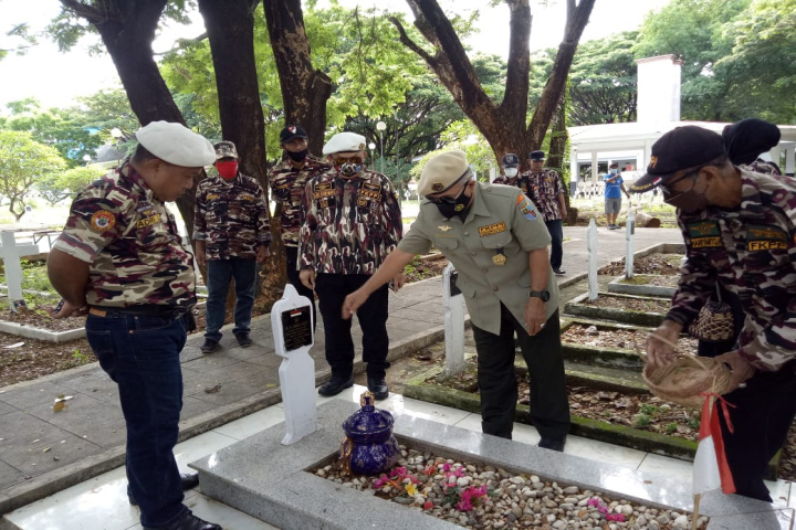 Plt Ketua FKPPI Sulsel Suwandi mahendra seragam coklat taburkan bunga ke makam pahlawan. (Foto: Istimewa).