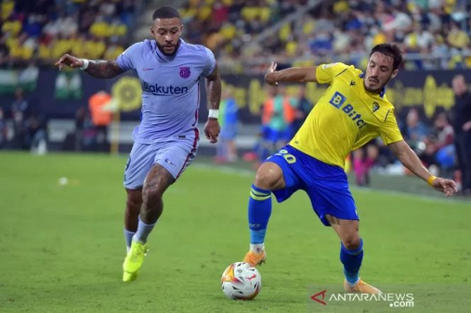					Penyerang Barcelona Memphis Depay (kiri) berduel dengan bek Cadiz Iza Carcelen untuk memperebutkan bola dalam pertandingan Liga Spanyol di Estadio Nuevo Mirandilla pada 24 September 2021. ANTARA/AFP/CRISTINA QUICLER.