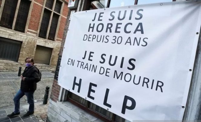 					Arsip - Seorang warga berjalan melewati poster yang diletakkan di jalan masuk ke restoran di Brussels, Belgia, Rabu (14/4/2021), saat penyebaran penyakit virus corona (COVID-19) terus berlanjut. Poster itu bertuliskan 