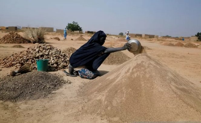 					Ouedraogo Rasmata, 55, yang menyelamatkan diri dari serangan militan bersenjata di wilayah Sahel bagian Soum menyiapkan pasir untuk dijual kepada pekerja konstruksi di kamp tak resmi bagi warga terlantar di pinggiran Ouagadougou, Burkina Faso, Kamis (19/11/2020). REUTERS/Zohra Bensemra /WSJ/djo (REUTERS/ZOHRA BENSEMRA)