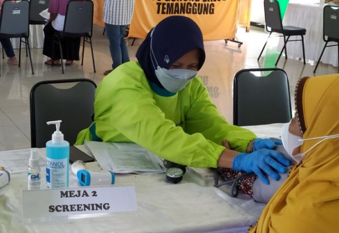 					Petugas tenaga kesehatan saat memeriksa kondisi seorang lansia yang akan menjalani vaksinasi.