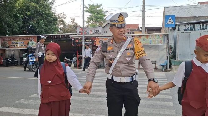 					Kasat Lantas Polres Sinjai, Iptu H sukri Liwang Menyebrangkan Anak sekolah. (Foto: Ist/ Humas)