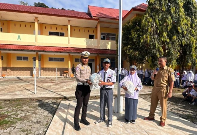 					Kanit Regident Polres Sinjai, Ipda Ramli Maulid Serahkan Helm SNI ke Salah Satu Siswa. (Foto: Istimewa)