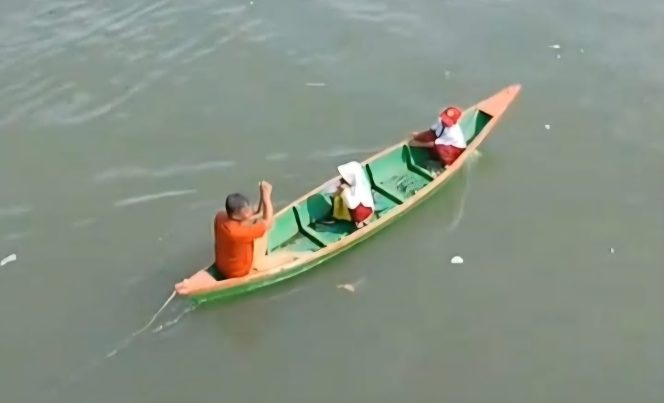 					Ali Mappaompo Sedang Mendayung Perahu Membawa Dua Muridnya Menuju Sekolah. (Foto: Humas AGPAII Sinjai)