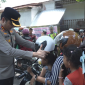 Kapolres Gowa memasangkan helm kepada pengendara anak saat pembagian 100 helm gratis sebagai upaya meningkatkan kesadaran keselamatan berlalu lintas. Foto: Ist