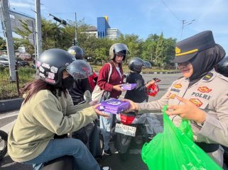 Seorang polwan Polres Maros  membagikan bingkisan kepada buruh. Ist