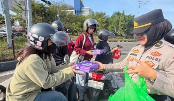 Seorang polwan Polres Maros  membagikan bingkisan kepada buruh. Ist