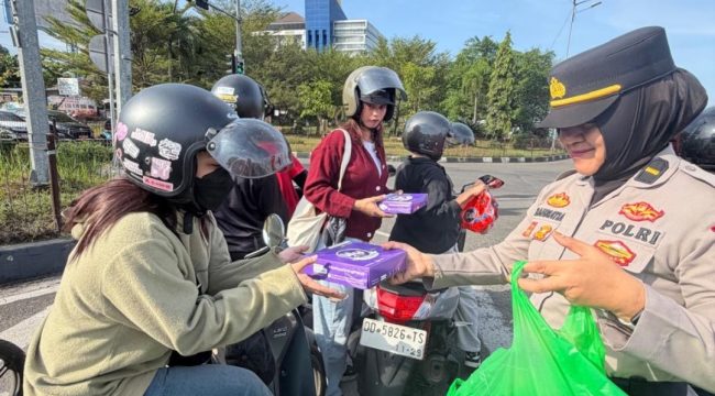 Seorang polwan Polres Maros  membagikan bingkisan kepada buruh. Ist