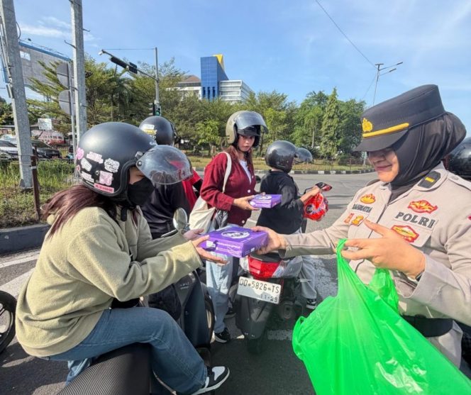 					Seorang polwan Polres Maros  membagikan bingkisan kepada buruh. Ist